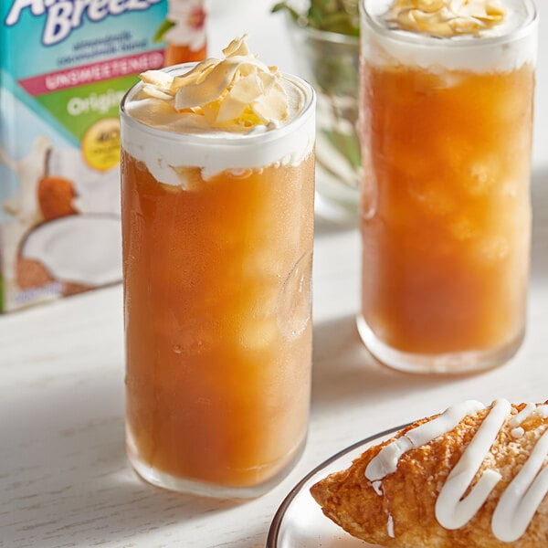 A glass of Almond Breeze Almond and Coconut milk with a pastry on a plate.