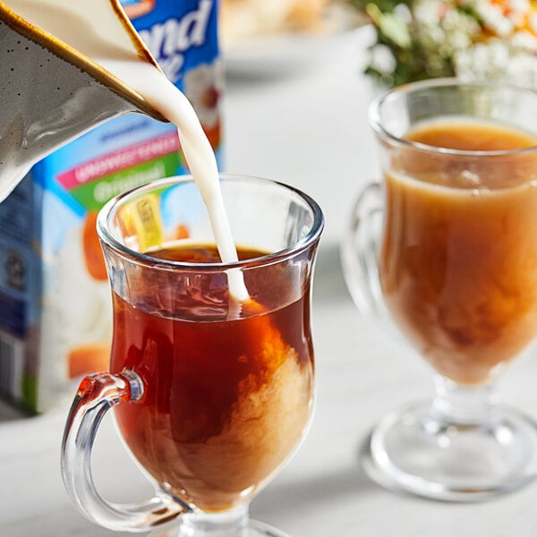A close-up of Almond Breeze unsweetened almond milk being poured into a glass of liquid.