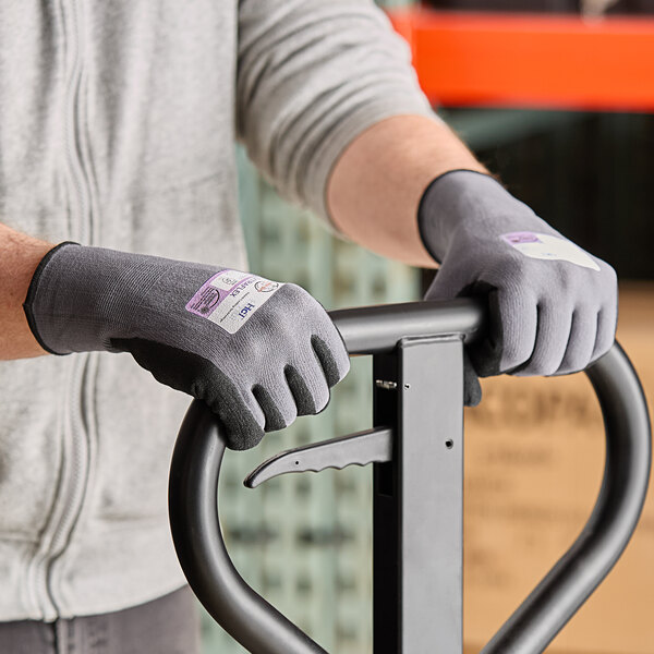 A person wearing Armor Guys heavy duty work gloves with black palm coating holding a metal bar.