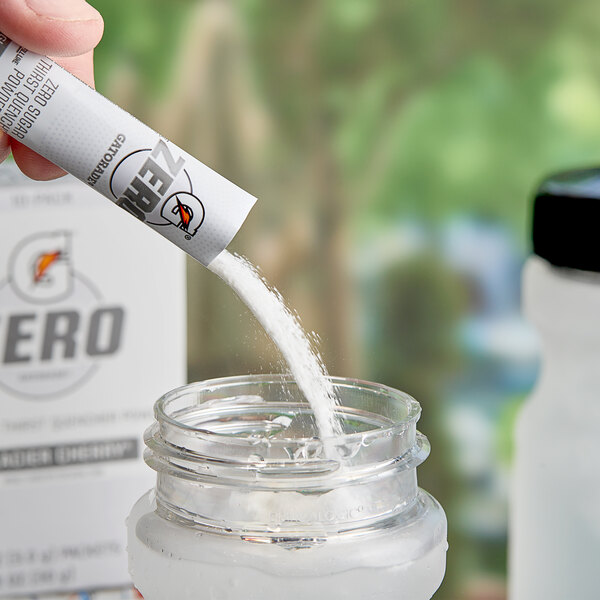 A hand pouring Gatorade Zero Sugar Glacier Cherry powder into a jar.
