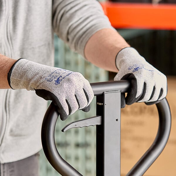 A person wearing Armor Guys Basetek heavy duty gloves with nitrile palm coating holding a metal bar.