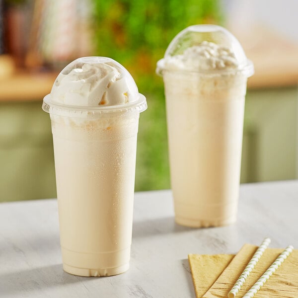 Two Choice clear PET plastic cold cups with dome lids on a table with straws.