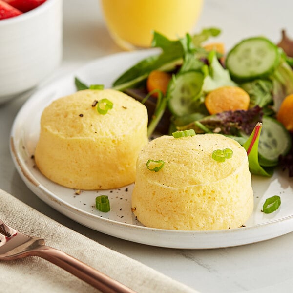 Two White Toque cheese egg bites on a plate with a salad.