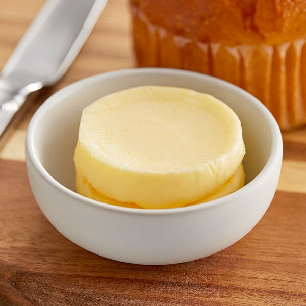 A bowl of Echire butter with a knife next to it on a table.