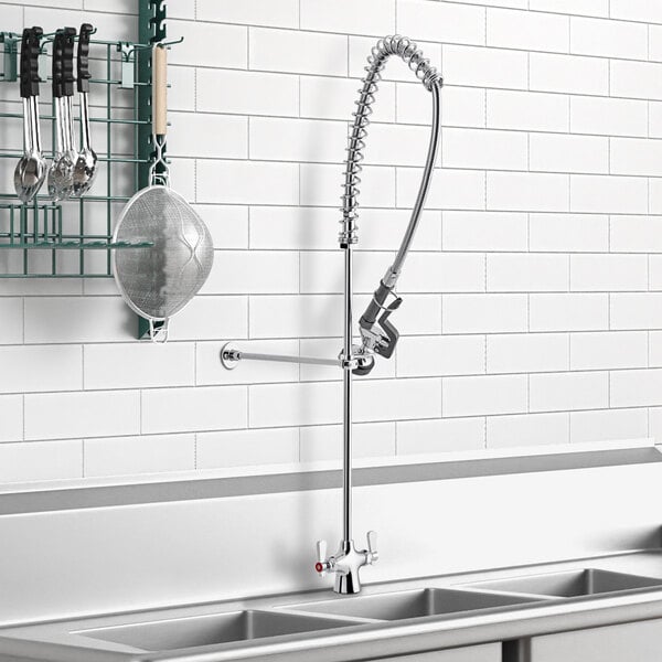 A sink with the Assure Parts deck-mounted pre-rinse faucet and a rack of utensils.