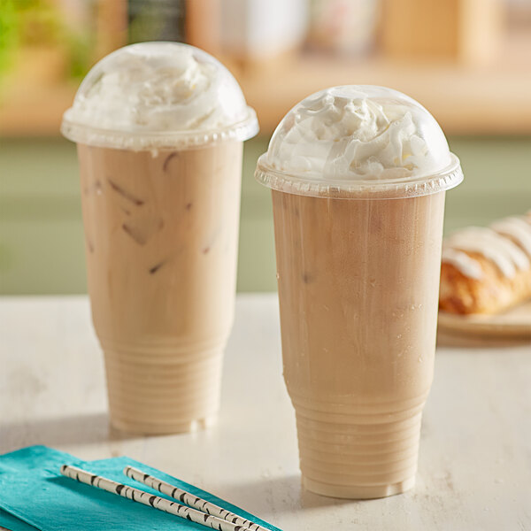 Two Choice clear plastic cups of coffee with whipped cream and straws.