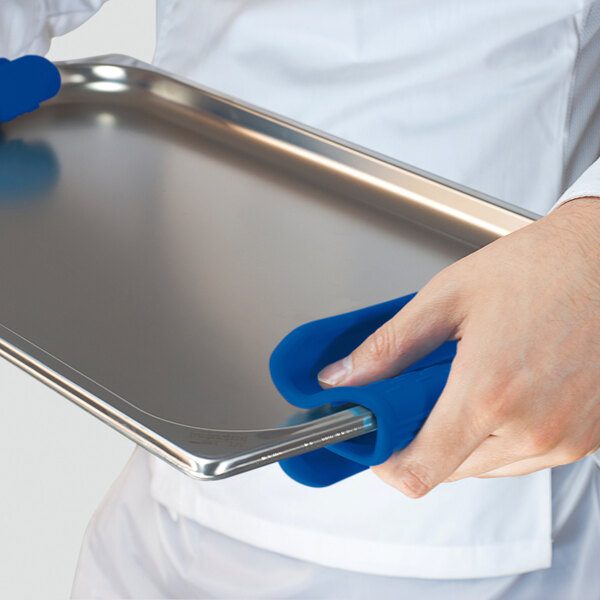 A person using a blue Araven silicone pot holder to carry a tray.