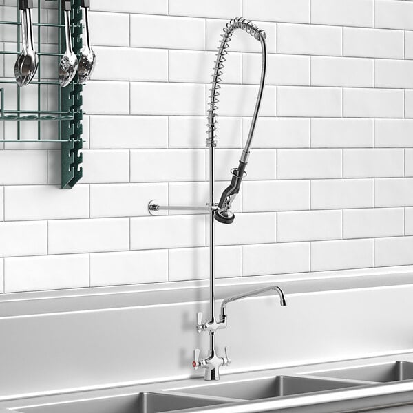 A sink with a Deck-Mounted Pre-Rinse Faucet and 12" Add-On Faucet over a rack of dishes in a professional kitchen.