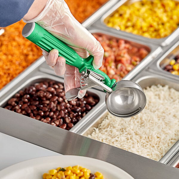 A person using a Fourté Green Thumb press disher with a green handle to serve food.