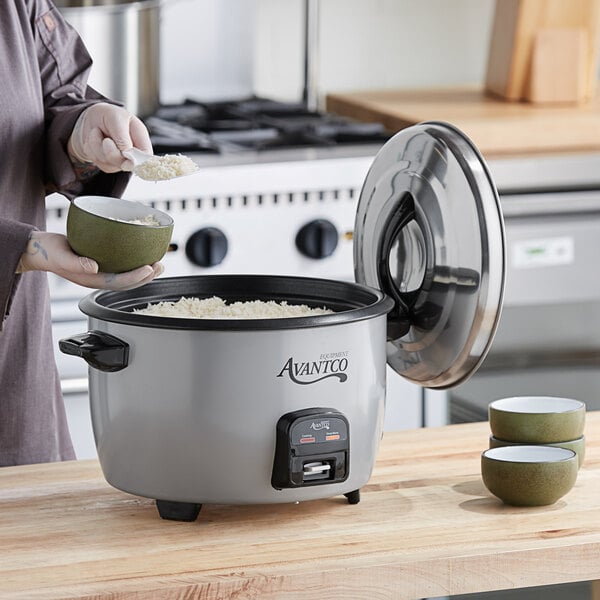 A woman pouring rice into an Avantco commercial rice cooker.