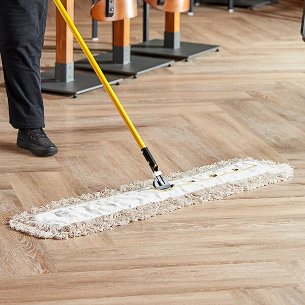 A person using a Lavex dry mop to clean a floor.