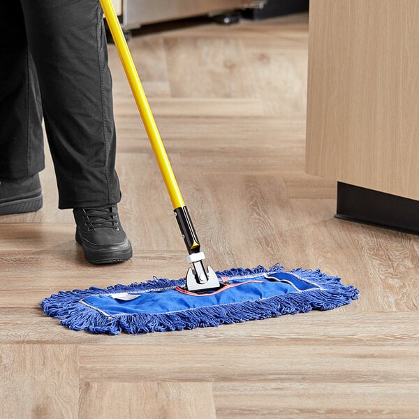 A person using a Lavex blue cotton blend dry dust mop to clean a floor.