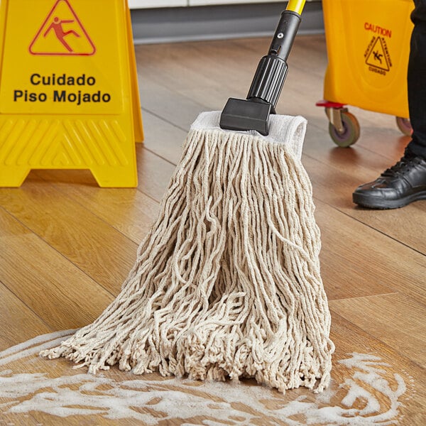 A person mops the floor with a Choice natural cotton mop head.
