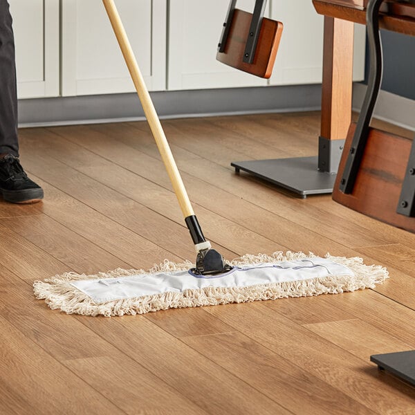 A Lavex white cotton looped end mop head on a wood floor.