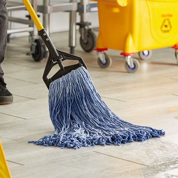 A person cleaning a floor in a hospital cafeteria with a Lavex Blue Rayon Cut-End Mop.