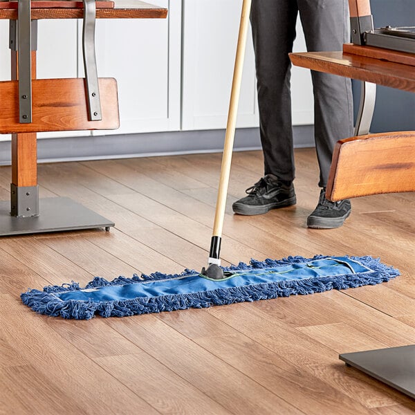 A person using a Lavex Blue Cotton Blend Dry Dust Mop to clean a wooden floor.