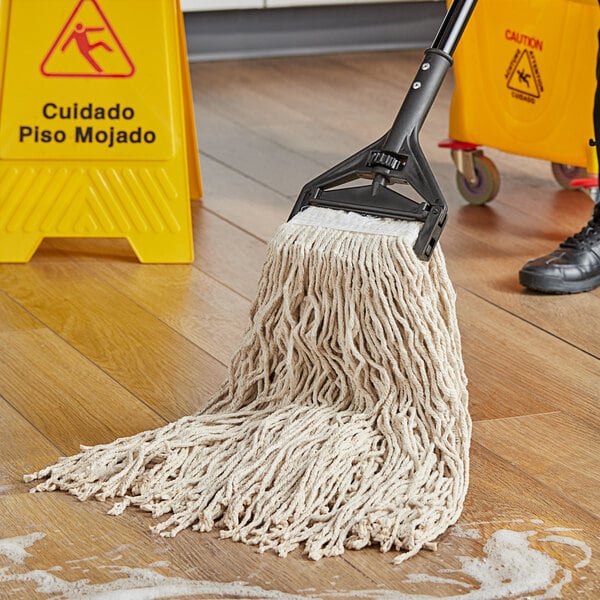 A person mopping a floor with a Choice Natural Cotton Cut-End Mop Head.