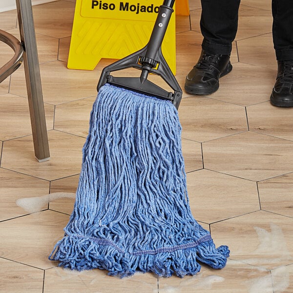 A person mopping a tile floor with a blue Lavex cotton blend mop.