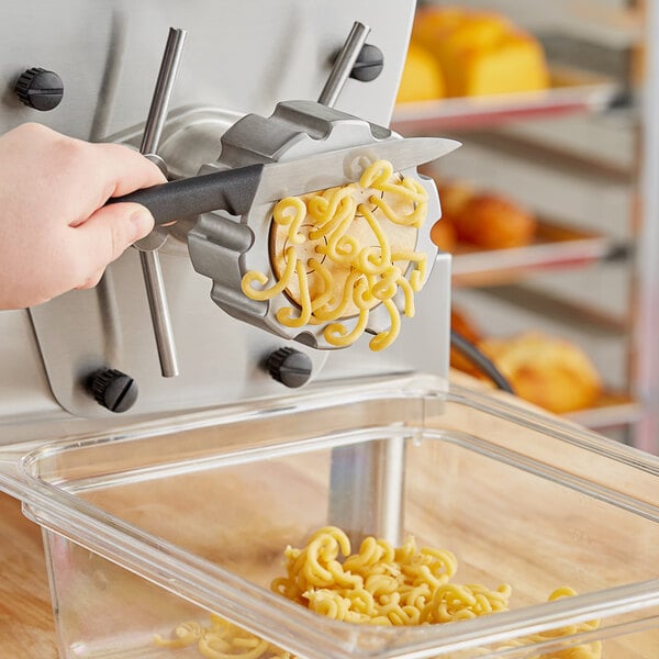 A person using an Estella pasta machine to cut noodles.