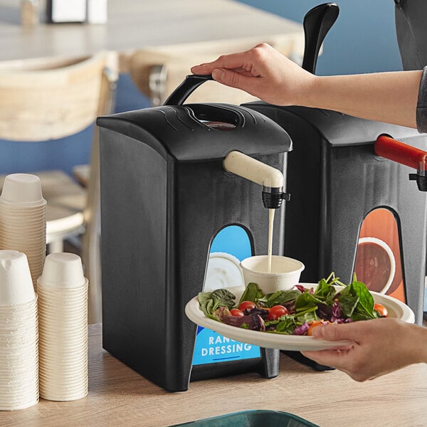 A woman using a ServSense ranch pouch dispenser to pour salad dressing onto a bowl of salad.