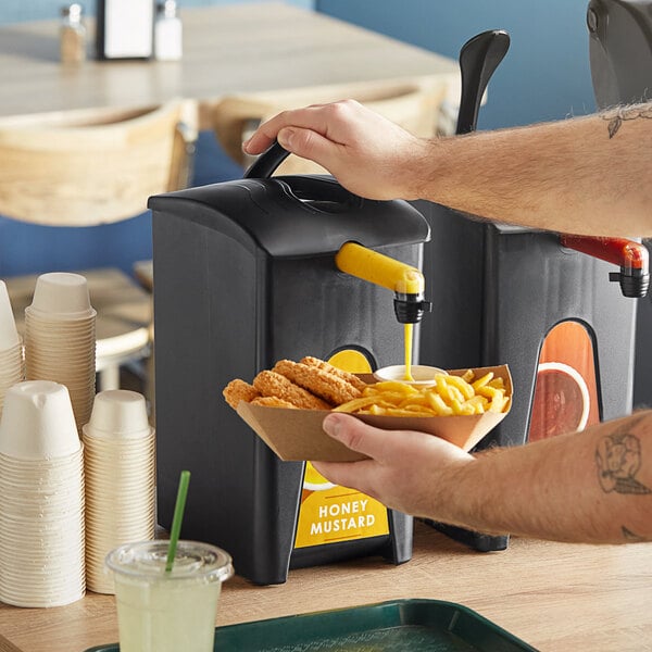 A person using a ServSense honey mustard dispenser to pour sauce onto chicken nuggets.