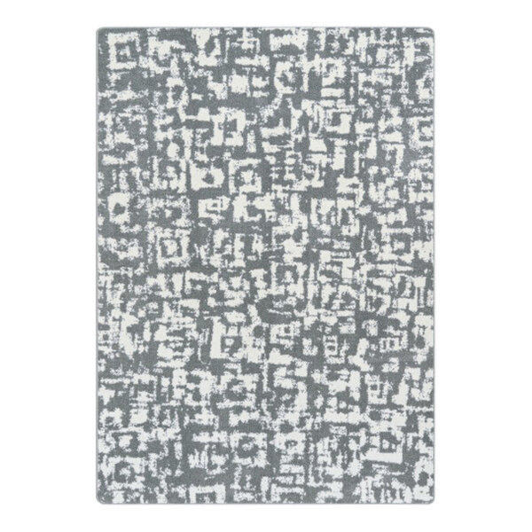 A close-up of a Joy Carpets grey and white block print area rug with abstract designs.