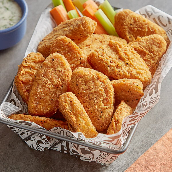 A basket filled with Tindle plant-based chicken wings and carrots on a table.