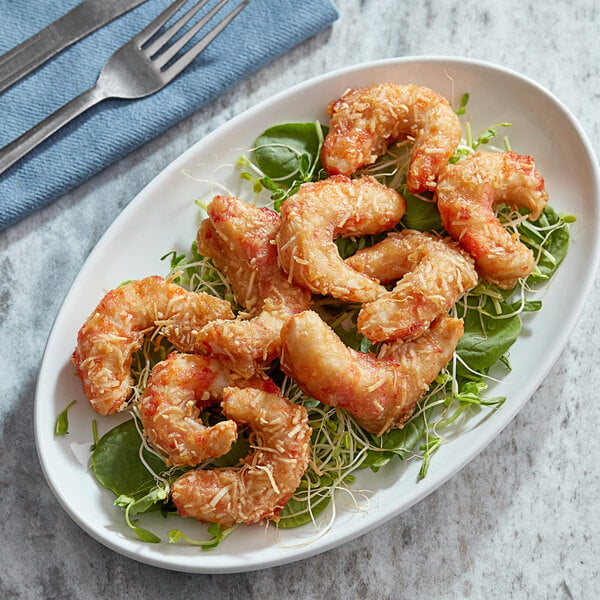 A plate of fried Mind Blown vegan coconut shrimp with a fork and knife on a blue cloth.