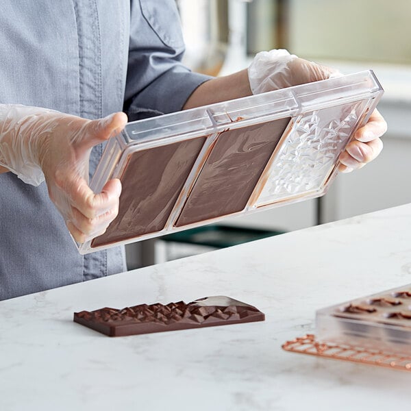 A person holding a Pavoni polycarbonate tray of chocolate bars.