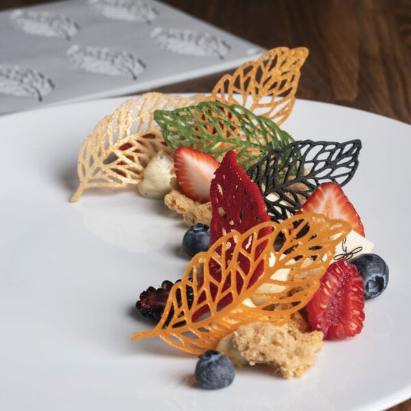 A white tray with Pavoni Gourmand Plume silicone baking molds on it, each mold has a leaf and berry imprint.