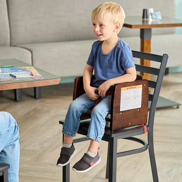 A wooden booster seat with a dark brown finish placed on a chair.