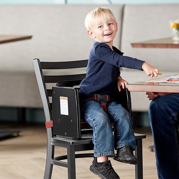 A child sitting in a Lancaster Table & Seating wooden booster seat at a table.