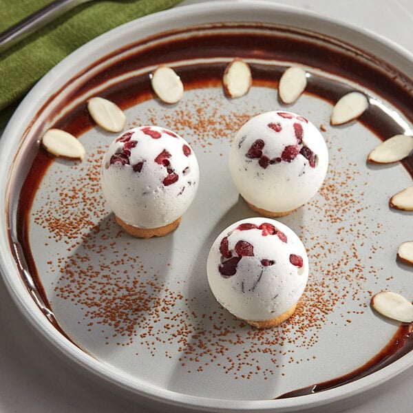 Three chocolate sphere desserts on a plate.