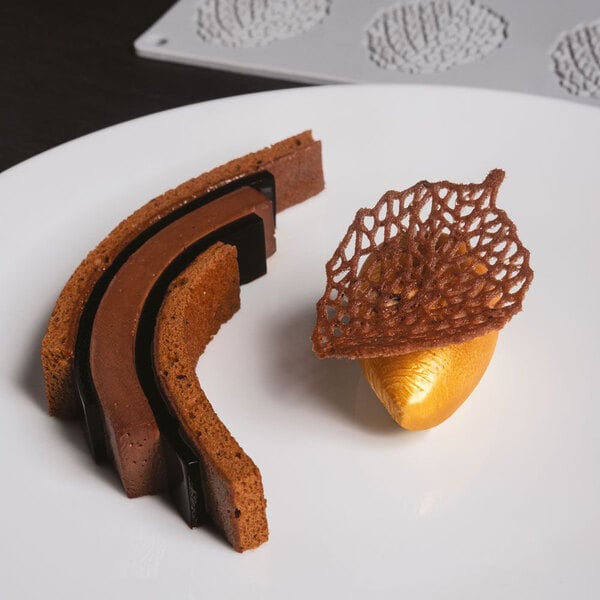 A chocolate and caramel dessert made with a Pavoni Gourmand leaf silicone baking mold on a white plate.