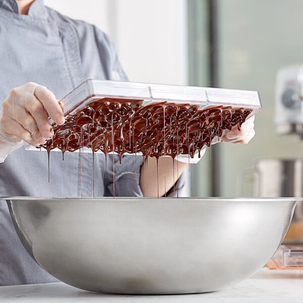 A woman in a chef's uniform pouring chocolate into a Pavoni Eros chocolate bar mold.