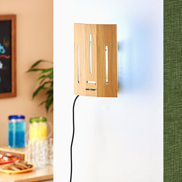 A wooden rectangular Lavex Zap N Trap wall sconce with a blue and white light and cord attached to it.
