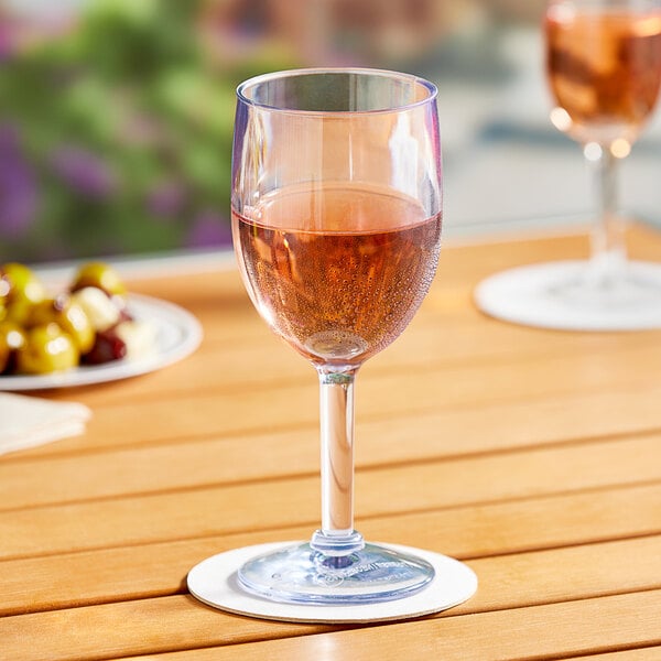 A Choice plastic wine glass filled with pink liquid on a table outdoors.