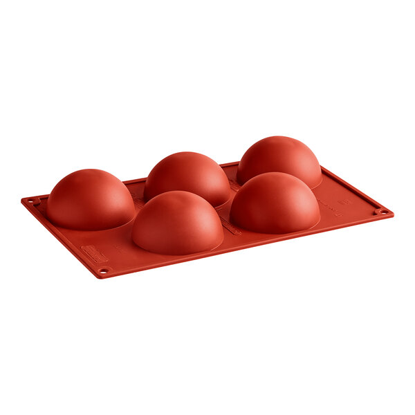 A red silicone baking tray with round cavities.