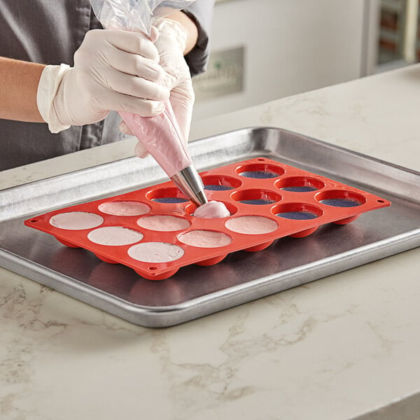 A person using a Pavoni Formaflex round silicone baking mold to fill a pastry bag.