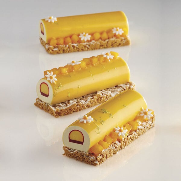 A group of yellow and orange Pavoni Pavoflex desserts on a white surface.