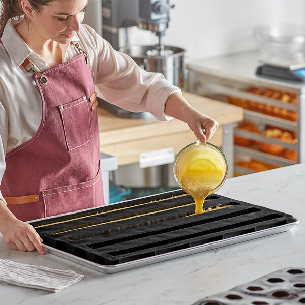 A woman pouring liquid into a Pavoni silicone baking mold.