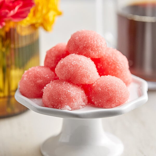 A white plate with pink Pavoni semi-sphere candies.