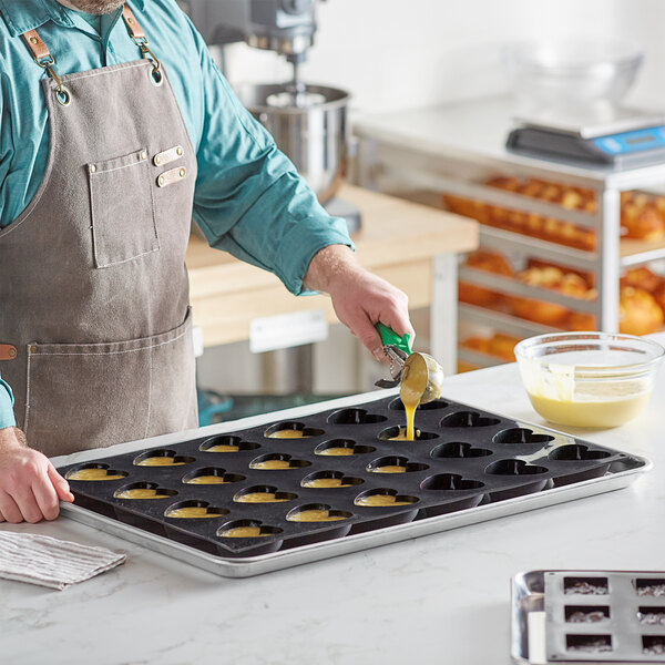 A person in an apron pouring batter into a Pavoni Pavoflex silicone baking mold.