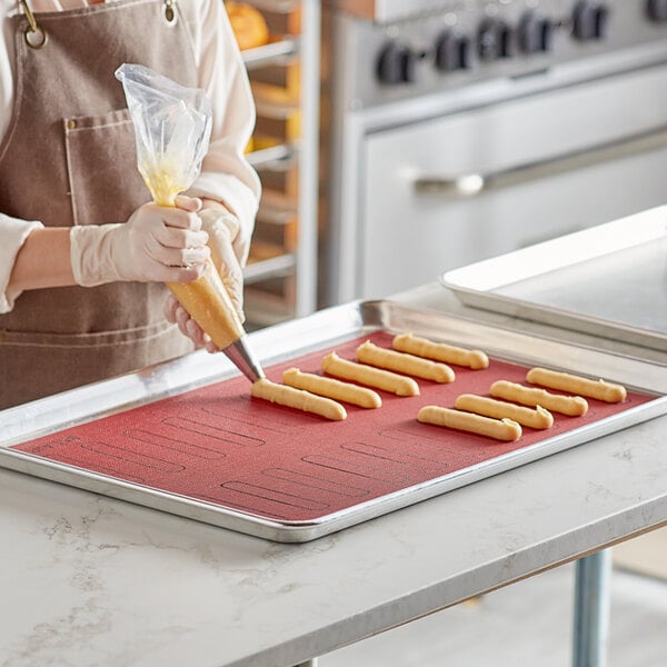 A woman in a kitchen using a Pavoni micro-perforated silicone baking mat to make pastry.