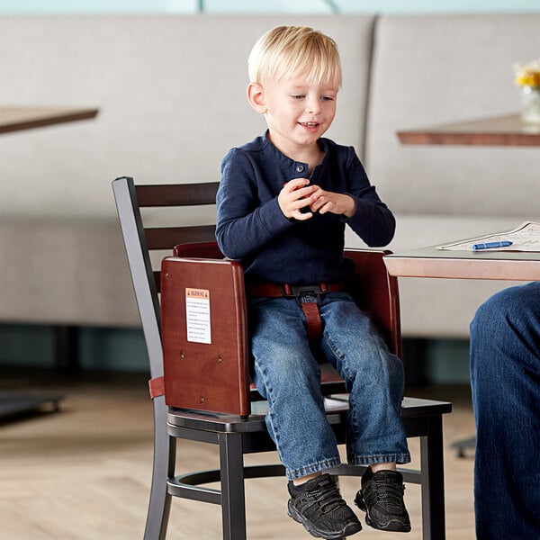 A man and a boy sitting in Lancaster Table & Seating mahogany wooden booster seats at a table.