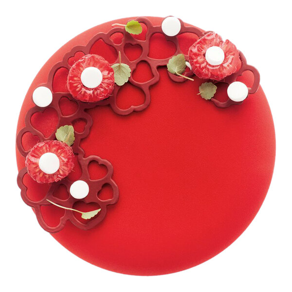 A Pavoni Pavodecor heart silicone baking mold on a table with a red cake decorated with strawberries and leaves.