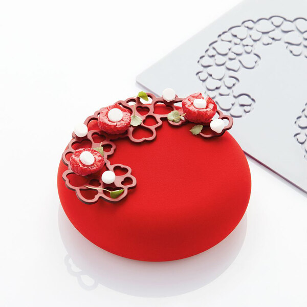 A red round cake with heart-shaped decorations on top.