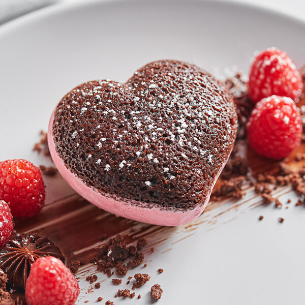 A heart shaped chocolate cake made with Pavoni Pavoflex Passion baking mold on a plate with raspberries.