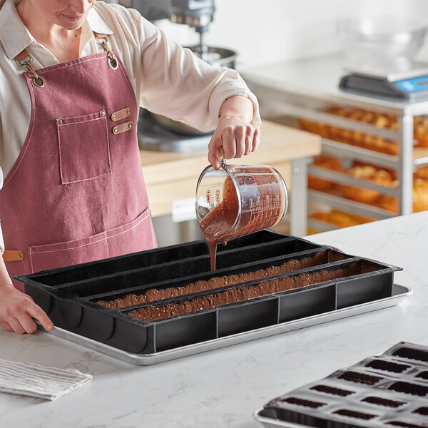 A woman pouring chocolate into a Pavoni Pavoflex silicone baking mold.