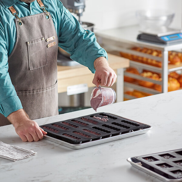 A man in an apron pouring food into a Pavoni Domino silicone baking tray.